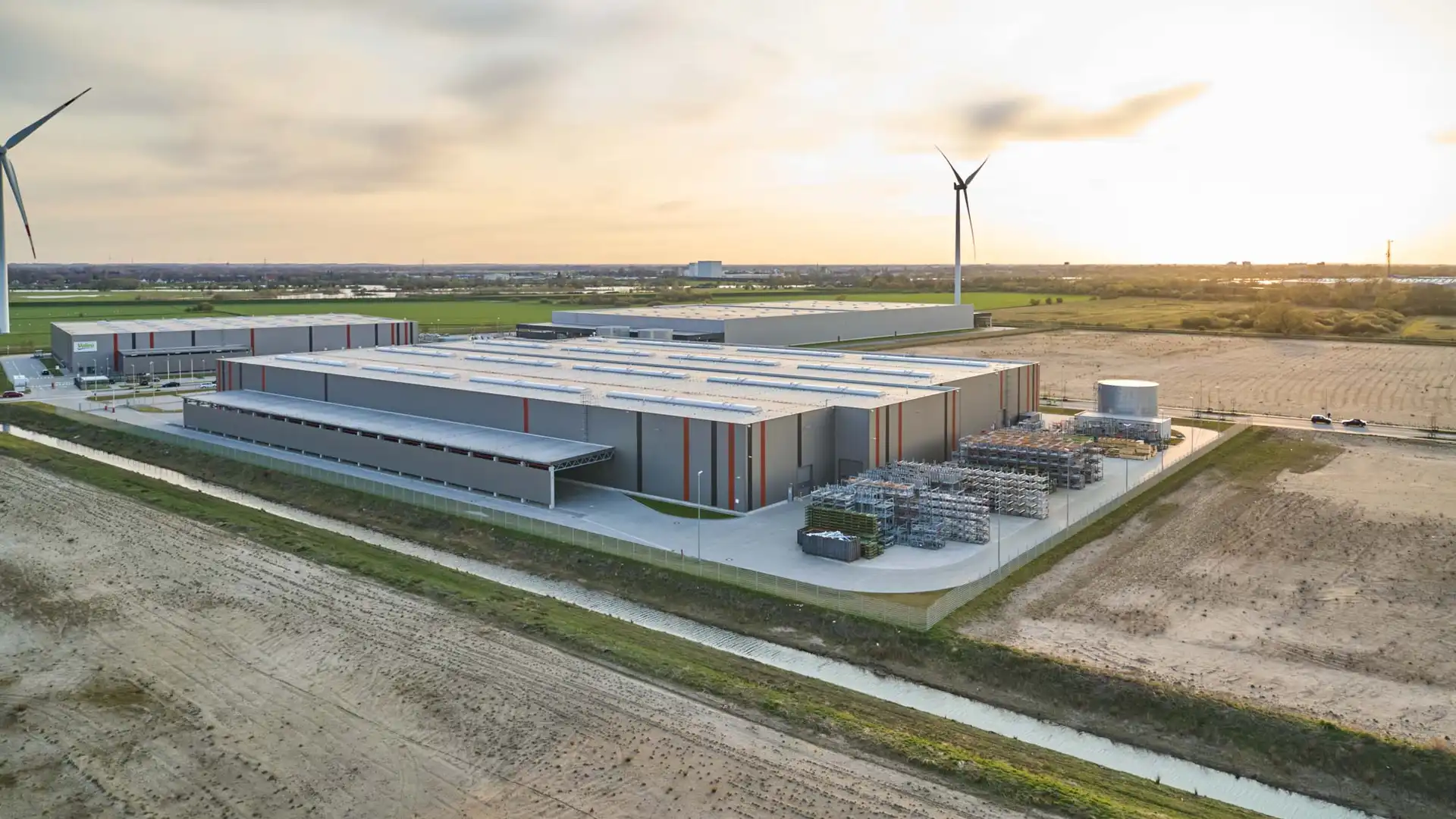 Luftaufnahme der Lagerhalle Hansalinie Bremen - Linde + Wiemann. Dargestellt sind zwei große Lagerhallen mit verschiedenen Materialien, die davor gestapelt sind.