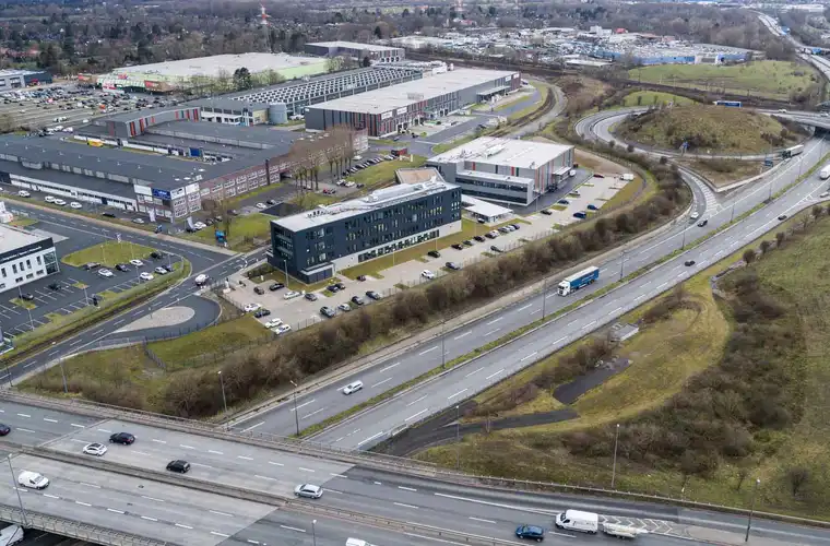 Luftaufnahme des Geländes "Lloyd Industriepark Bremen". Abgebildet werden verschiedene Gebäude und Lagerhallen. Das Gelände ist weitläufig, begrünt und mit verschiedenen Parkplätzen ausgestattet.